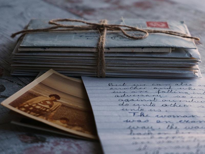 Fotografía de cartas atadas con una cuerda. Se ve una de ellas abierta y una foto en el mar de una mujer y une niñe.