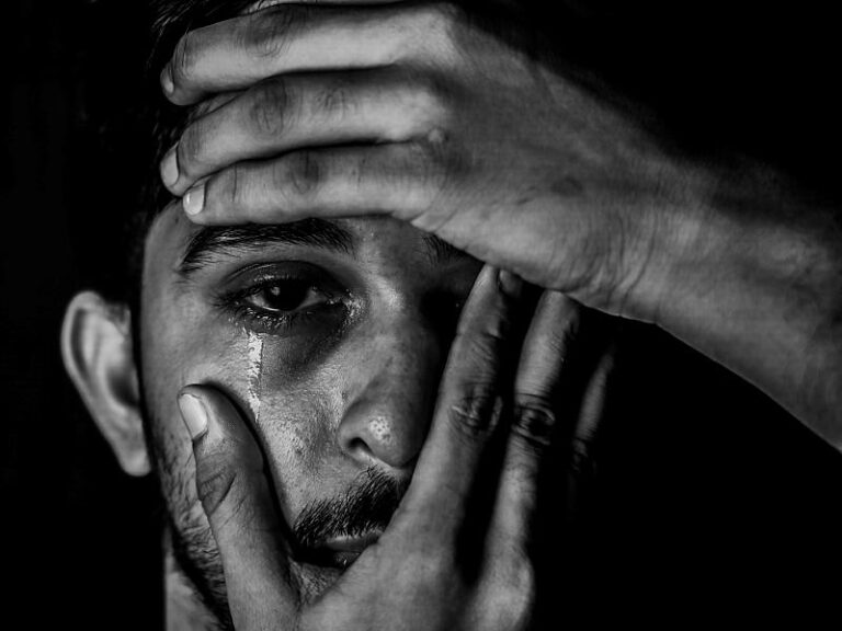 Hombre joven se sujeta la cabeza y se abre el ojo derecho mientras llora.