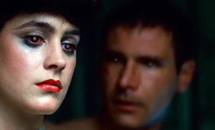 Imagen de la película de Blade Runner donde sale Rachel, el personaje que interpreta Sean Young, en primer plano y Deckar, el personaje que interpreta Harrison Ford, en segundo plano mirándola.