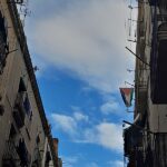 Foto de cielo con nubes que se ve a través de las líneas paralelas de los tejados de dos edificios enfrentados.