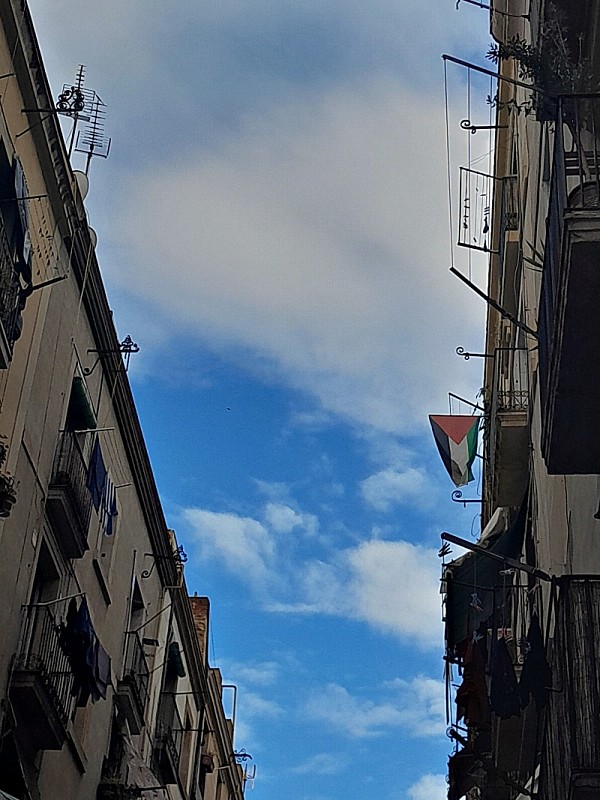 Foto de cielo con nubes que se ve a través de las líneas paralelas de los tejados de dos edificios enfrentados.