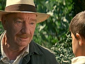 Fotograma de la película "La lengua de las mariposas". Primer plano de Fernando Fernán Gómez con sombrero mirando al niño protagonista que está de espaldas. Están en el campo.